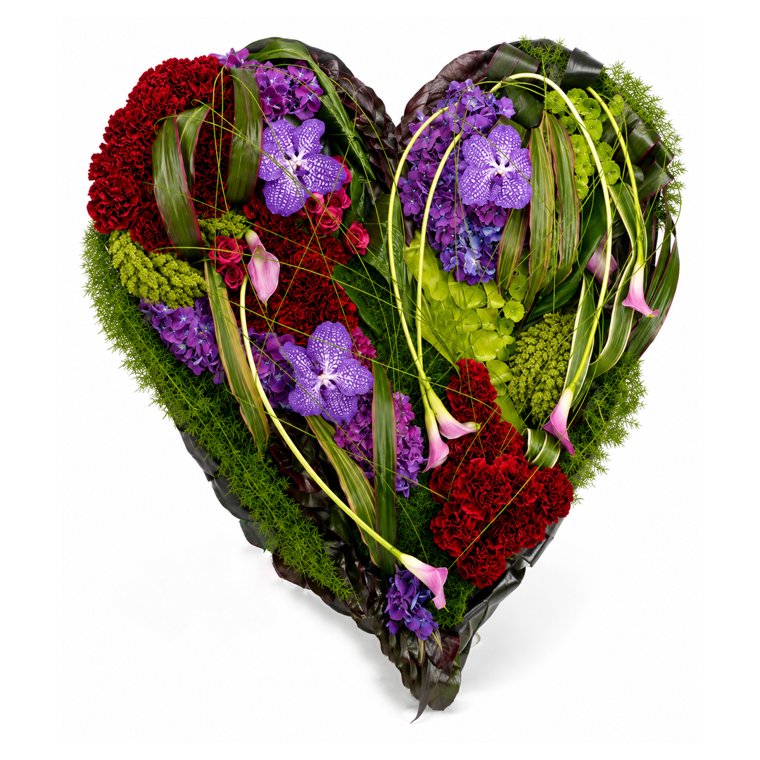 A heart-shaped floral arrangement featuring vibrant red carnations, purple orchids, pink calla lilies, and green foliage on a solid white background.